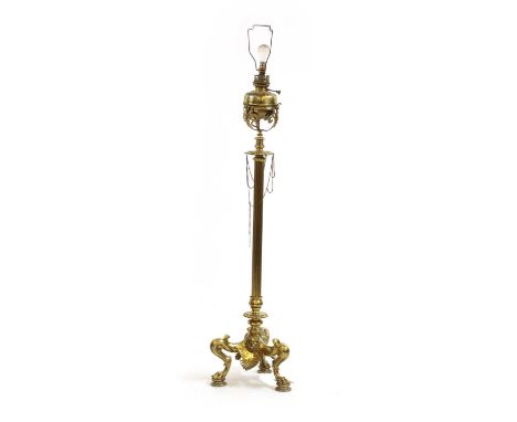 A brass standard lamp, the adjustable, reeded column on a bold tripod base, cast with shells and lion's paws. Formerly an oil