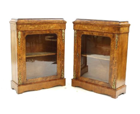 A pair of strung walnut and crossbanded marquetry inlaid pier cabinets, with brass mounts flanking a central glazed door, on 