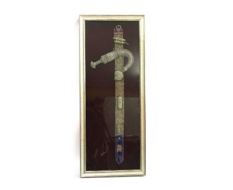 A Omani Khanjar dagger, with a silver handle and scabbard on a belt with fittings, in a glazed case, 49.5cm x 121cm