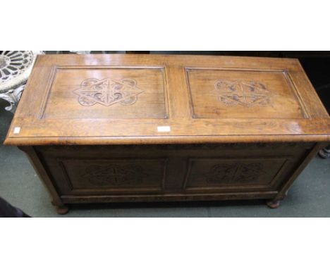A 20th century oak trunk with carved panels to front and lid