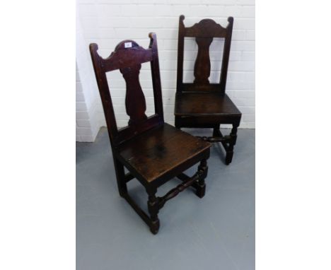 A pair of early 19th century oak hall chairs having moulded top rails over panel seats raised on turned supports and stretche