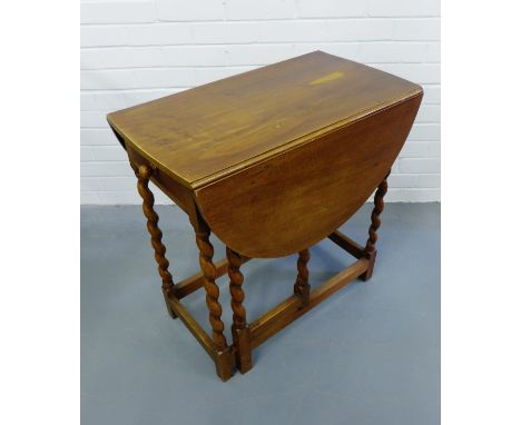 An Edwardian mahogany gate leg table having a moulded oval top over short drawer raised on barley twist supports and stretche