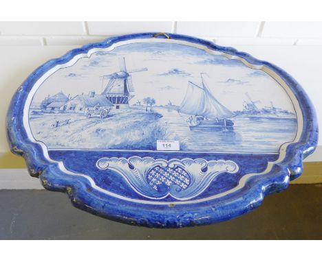 A large Delft oval wall plaque with scalloped rim and painted with a windmill and canal scene, 60 x 52cm 