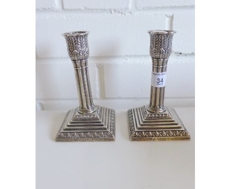 A pair of late Victorian dwarf silver table candlesticks, with corinthian column stems and leaf embossed sconce, raised on a 