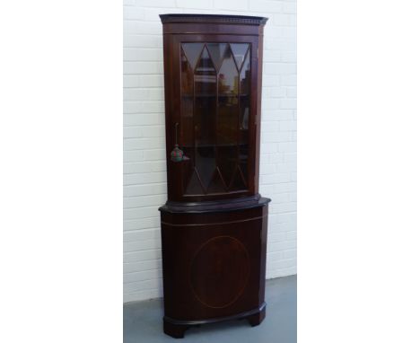 A mahogany corner cabinet having an astragal glazed panel door over panel doored cabinet raised on bracket feet, 66 x 182cm 