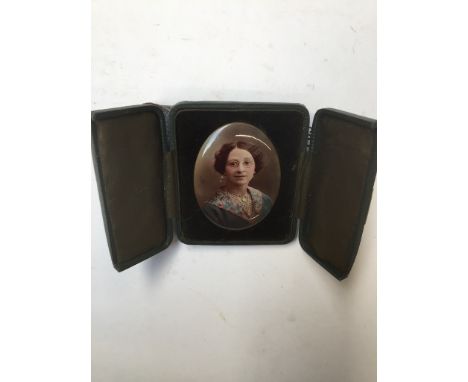 A photo portrait of a lady on centered tin in a bifold case. 