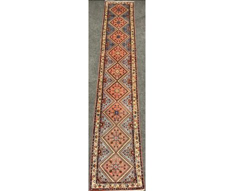 A North West Persian Rudbar Runner carpet, hand-knotted with a row of nine diamond-shaped medallions, within a field of styli