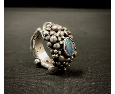 A modernist Michael Allen Bolton (Cornish) silver opal set ring, cast as a multi section rocky cluster, with central opal cab