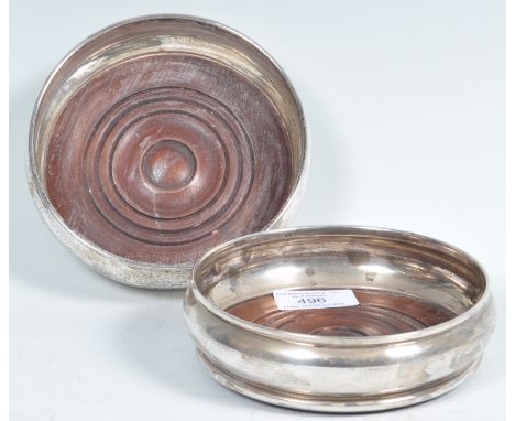 A pair of 20th Century hallmarked silver wine / champagne bottle coasters by David Shaw Silverware Ltd. Turned wooden bases w