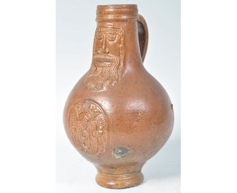A rare 17th Century German antique Bartmann / Bellarmine salt glazed stoneware wine jug having a bulbous body with decoration