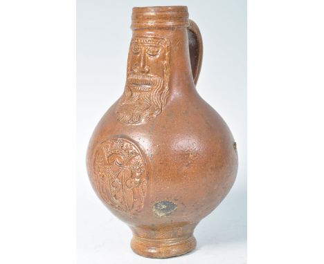 A rare 17th Century German antique Bartmann / Bellarmine salt glazed stoneware wine jug having a bulbous body with decoration