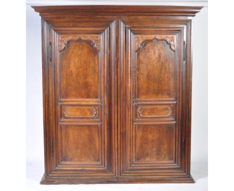 An antique 19th Century Dutch mahogany double wardrobe having inset panel twin doors with carved corner spandrels to the bord