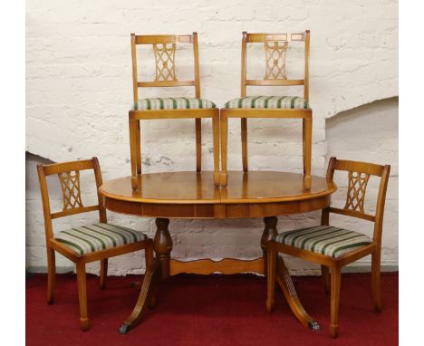 A yew wood extending twin pedestal dining table along with a set of four dining chairs raised on tapering spade feet.