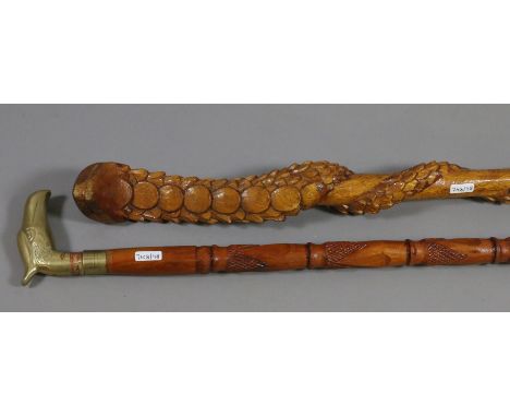 A carved novelty walking stick in the form of a python along with a brass top example.