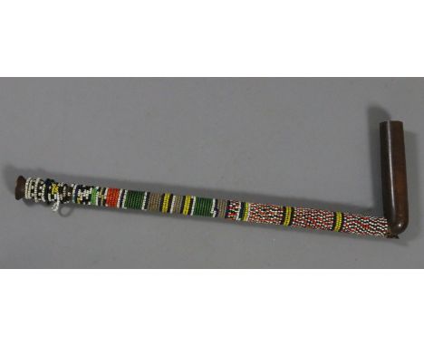 A turned hard wood pipe with beadwork decoration, pipe 15" long. Condition Report. To be used as a guide only. One head rest 