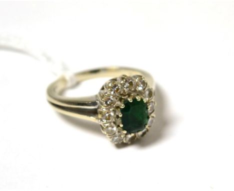 An emerald and diamond cluster ring, the emerald-cut emerald within a border of round brilliant cut diamonds, in white claw s