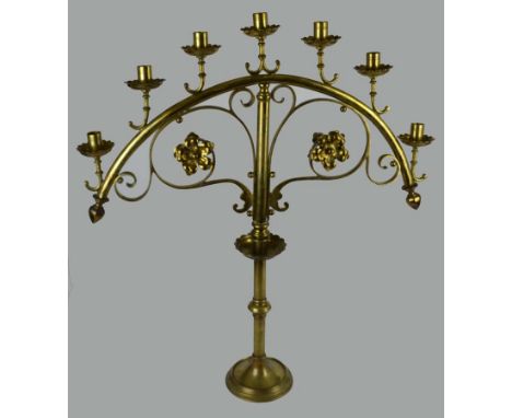 A large late 19thC brass Ecclesiastic seven light candelabra, the candle holders sitting on a curved frame with scroll and fo