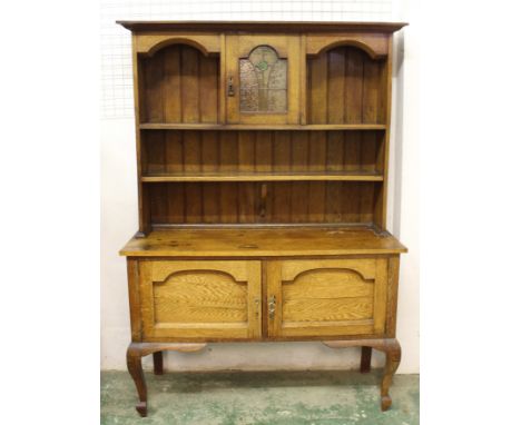 An oak Arts and Crafts sideboard/dresser, base unit with two doors each with deep panel, unit sitting on cabriole legs at fro