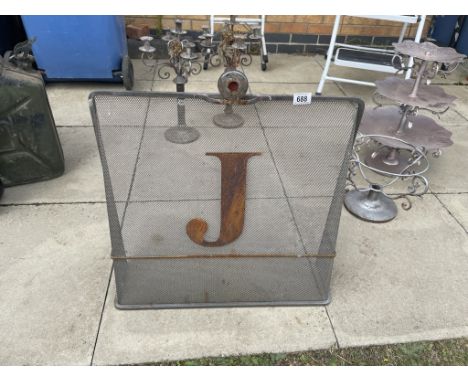 A vintage metal fire guard with letter J
