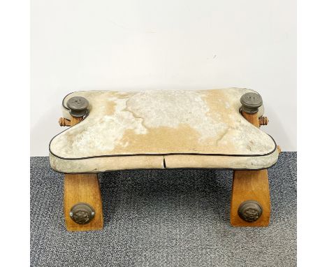 A camel skin covered camel saddle stool, L. 65cm.