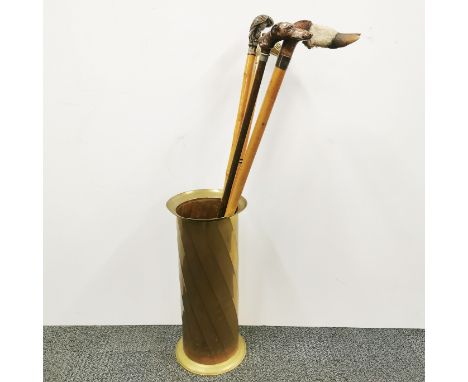 A brass umbrella stand with a group of four walking sticks.