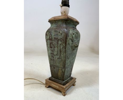 A heavy bronzed Eastern lamp base with geometric decorations on wooden base with wooden lid. H:27cm
