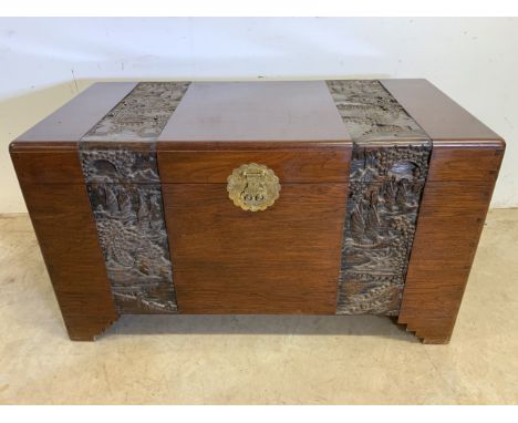 A good quality oriental rosewood and camphour wood trunk with carved panels depicting eastern life, large brass lock to the f