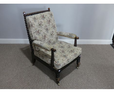 A Victorian ebonized wood and upholstered Armchair, with bobbin turned spindles, supports and stretchers, on turned legs with