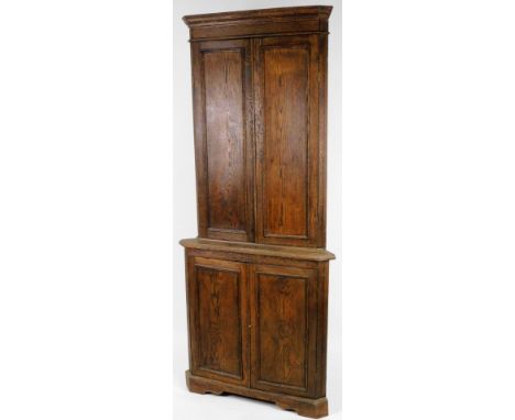 A 19thC oak free standing corner cupboard, the upper section with two panelled doors revealing shelves above a similar arrang