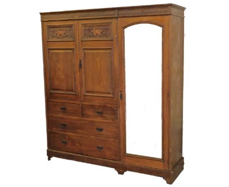 An early 20thC oak stained compactum wardrobe, each door heavily carved with scrolls and shields, above plain panels and two 