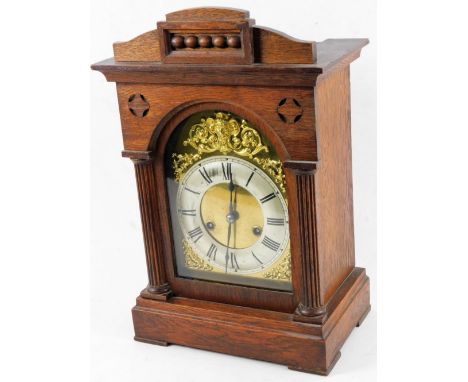 An Edwardian oak cased mantel clock, with orb pediment and quarter columns on a stepped base terminating in compressed feet, 