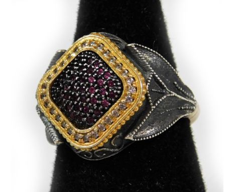 A ruby and diamond set gent's signet ring, of diamond form, with round brilliant cut rubies, in a claw setting, surrounded by