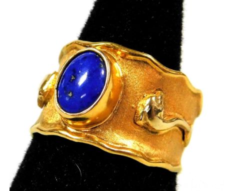 An Eastern style lapis serpent dress ring, with central oval cut lapis in rub over borders, on waved and brushed steel band, 