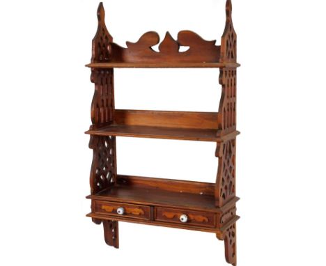 Am early 20thC stained hanging shelf, with three shelves, two drawers and side pierced supports, with a carved apron, 103cm H