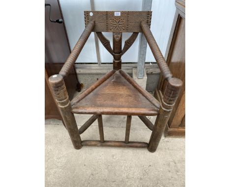 A HEAVILY CARVED OAK COCK FIGHTING CHAIR WITH BOBBIN TURNED ARMRESTS AND TRIANGULAR SEAT