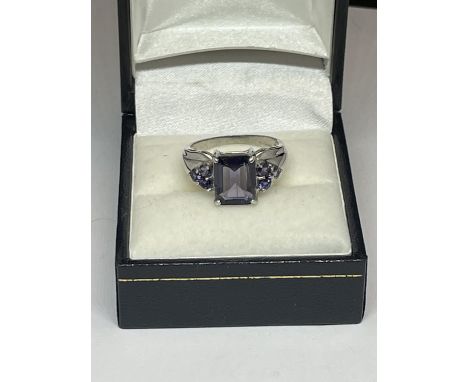 AN 18 CARAT WHITE GOLD RING WITH A LARGE RECTANGULAR BLUE STONE AND THREE BLUE STONES ON EACH SHOULDER IN A PRESENTATION BOX 