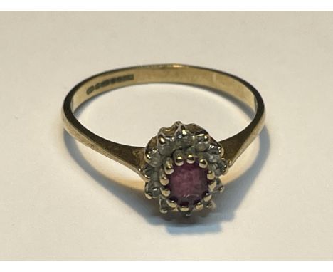 A 9 CARAT GOLD RING WITH A CENTRE RUBY SURROUNDED BY DIAMONDS SIZE O 