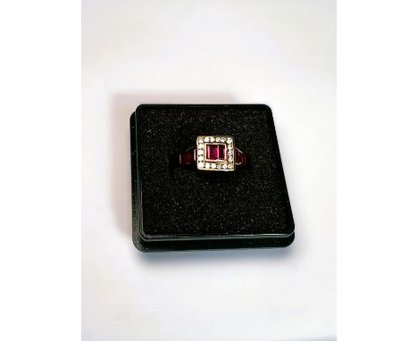 An 18ct gold Art Deco style dress ring set with ruby baguette cut stones surrounded by diamond square and more rubies to the 