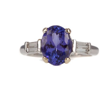 TANZANITE AND DIAMOND RING,the oval tanzanite of approximately 2.50 carats, flanked by pairs of baguette cut diamonds, in eig