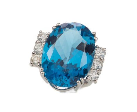 TOPAZ AND DIAMOND RING,set with an oval topaz of approximately 34.33 carats, flanked by round brilliant cut diamonds totallin