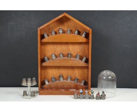 A collection of white metal and hallmarked silver thimbles together with a wall hanging thimble display case. 
