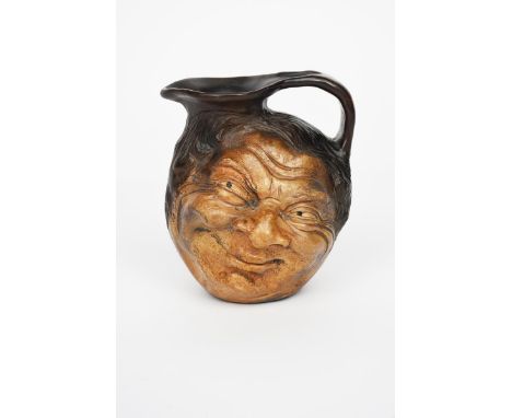 A Martin Brothers stoneware face jug by Robert Wallace Martin, modelled in relief with a smiling face to both  sides,  glazed