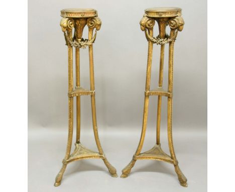 PAIR OF ADAMS STYLE GILTWOOD TORCHERES, early 19th century, the circular trays on tripod bases with floral wags between rams 