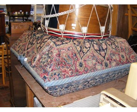 A square pouffe upholstered with Middle Eastern carpet fabric