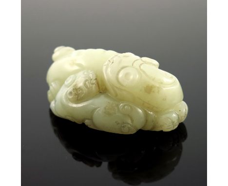 A Chinese pale jade netsuke, in the form of a recumbent shishi and infant, 5.5cm wide