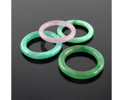 A series of three mottled green jade bangles, and a violet example, largest 8cm diameter (4)