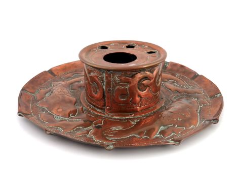 An Arts and Crafts Cornish copper inkwell, Newlyn style, the circular dish repousse decorated with fish and seaweed, the cyli