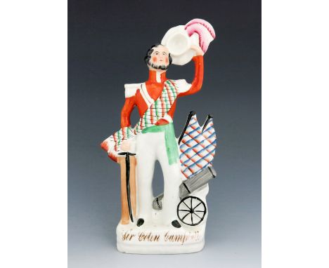 A Staffordshire figure of 'Sir Colin Campbell', circa 1857, modelled standing beside a cannon with flags, wearing an orange c