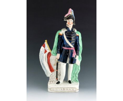 A Staffordshire Crimean War figure of General Windham, circa 1855, modelled standing beside a wall with a flag and cannonball