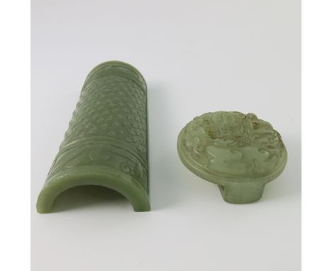 A Chinese green jade armrest, stud and beast carved, width 12.5cm, together with a circular jade buckle carved with a seated 